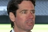 AFL CEO Gillon McLachlan speaks to media in front of an empty oval, wearing a suit.