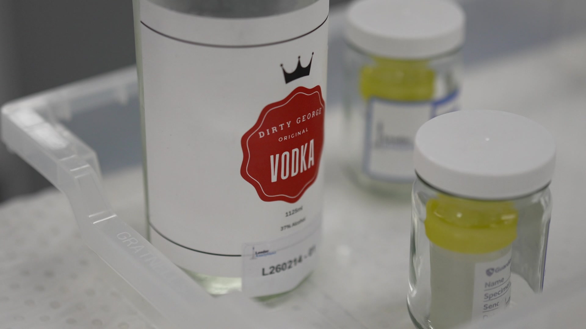A large bottle of vodka sitting in a tray for lab testing.