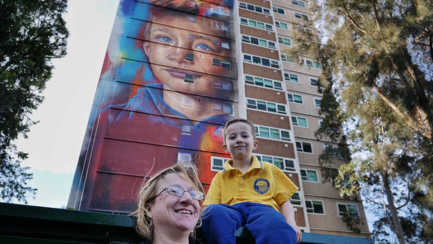 Six-year-old Arden Watson-Cropley with his mum in front of a mural of his face painted on a Collingwood housing commission flat.