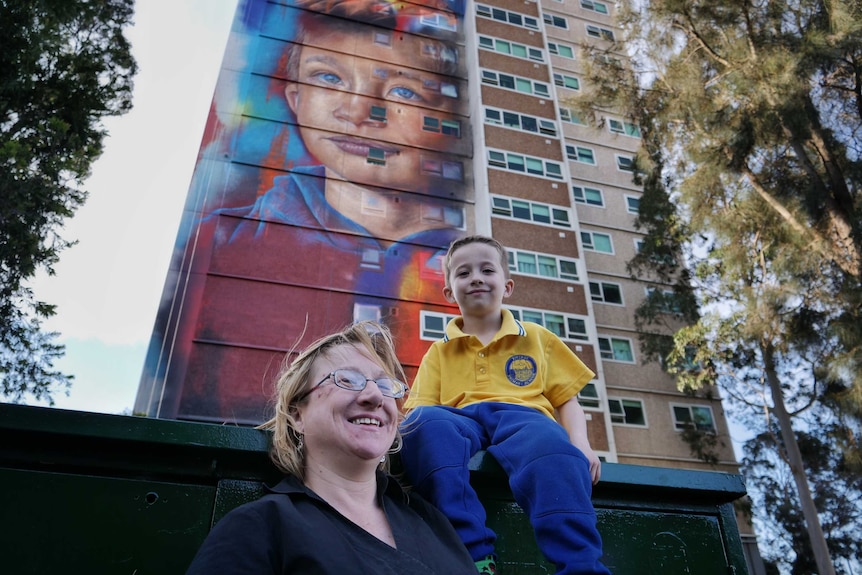 Six-year-old Arden Watson-Cropley with his mum in front of a mural of his face painted on a Collingwood housing commission flat.