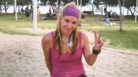 Missing woman Tina Greer smiles as she gives a 'peace' sign with her hand in a park.