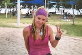 Missing woman Tina Greer smiles as she gives a 'peace' sign with her hand in a park.