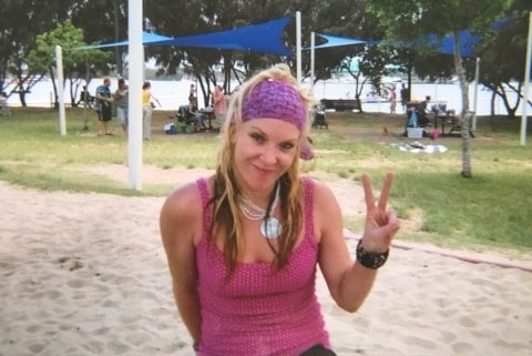 Missing woman Tina Greer smiles as she gives a 'peace' sign with her hand in a park.