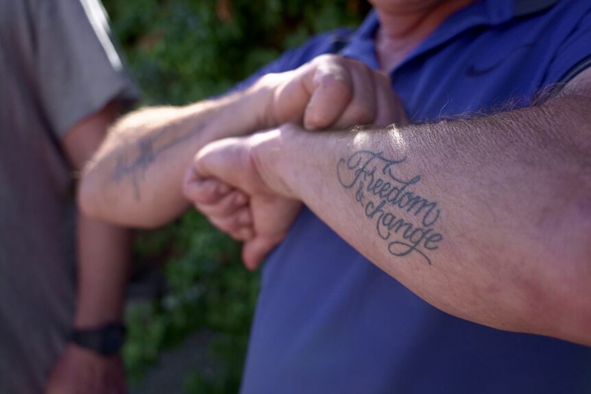 The words "freedom and change" tattooed on a man's arm.