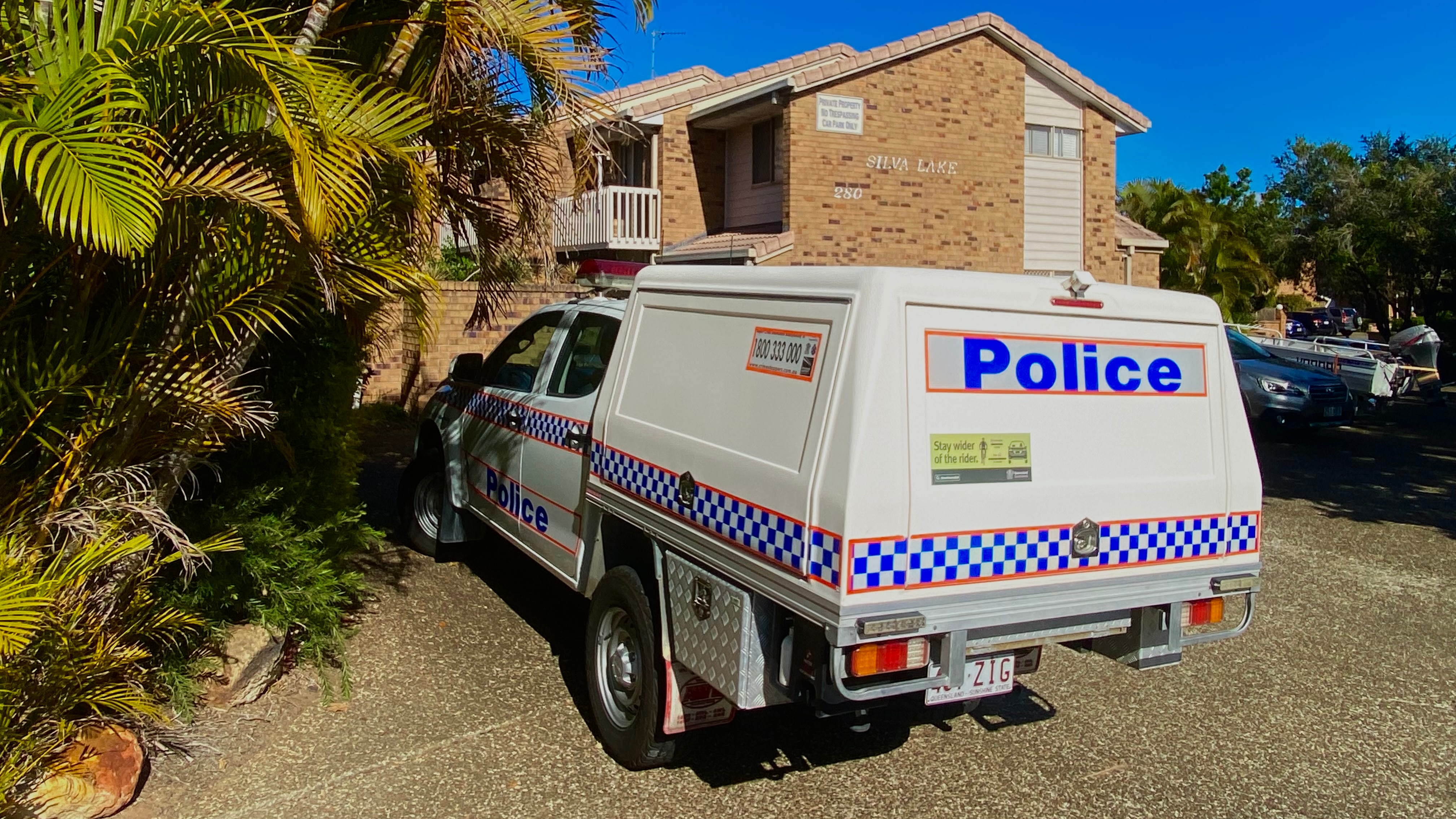 A police car parked in front of a brown-brick unit complex.