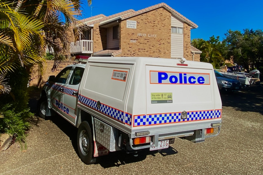 A police car parked in front of a brown-brick unit complex.