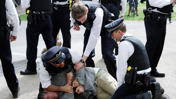 A protester is detained by police officers during a demonstration in Hyde Park, London.