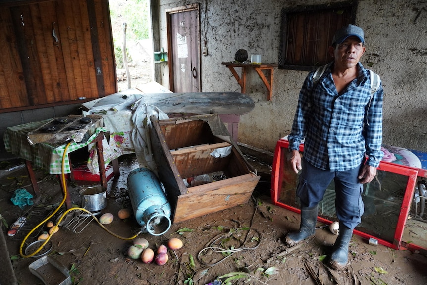 Meksykanin w czapce bejsbolowej wydaje się być w szoku w swoim zniszczonym domu