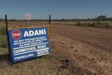 Sign reading Adani on the dirt road to it Carmichael mine site