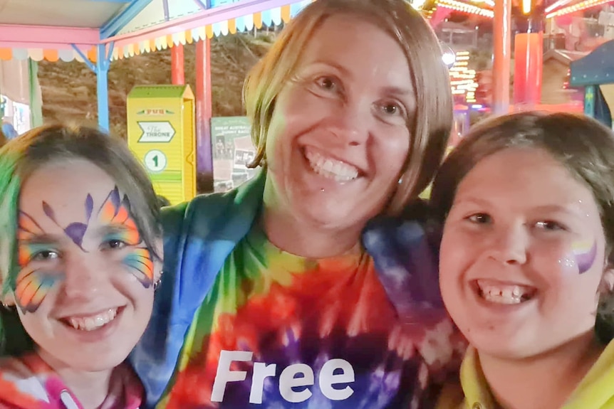 Mum with two children wearing rainbow tie-dye clothing, all with big smiles