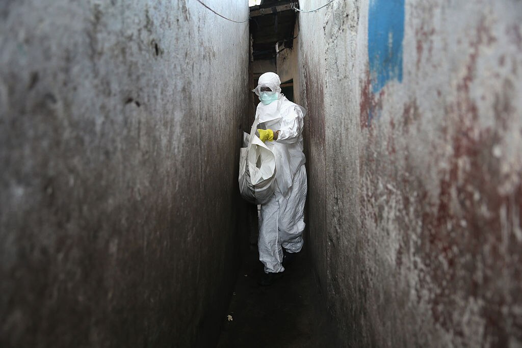 A health worker in ebola protective clothing carrying a white bag.