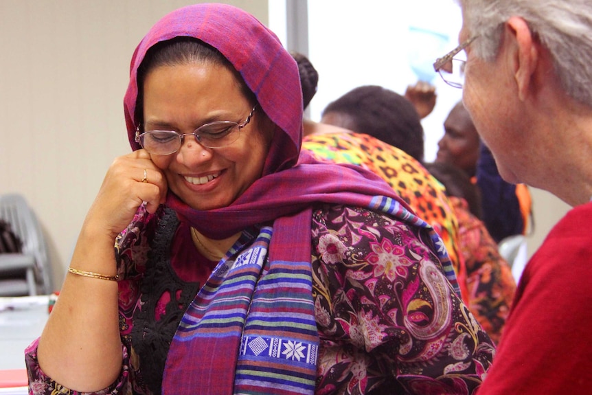 A woman laughing in conversation with another woman.