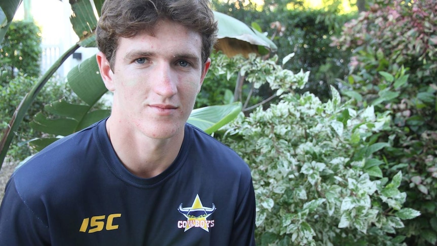 A young man in rugby league t shirt with ball in hand