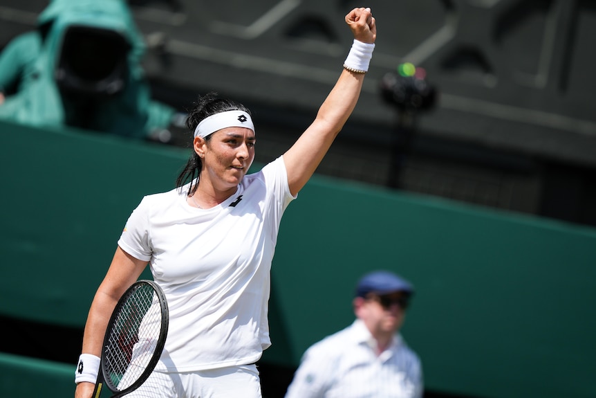 Tennis player Ons Jabeur raises her arm in triumph.