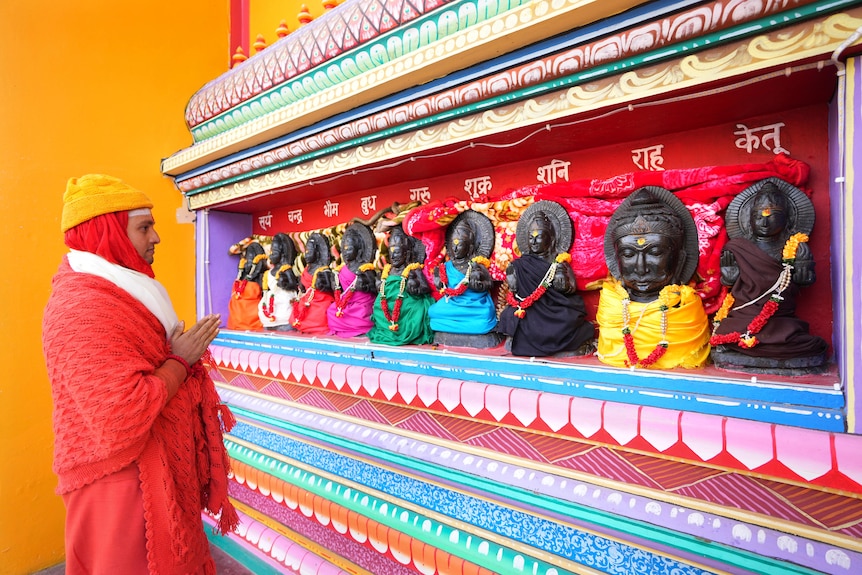 A man wearing red prays. 