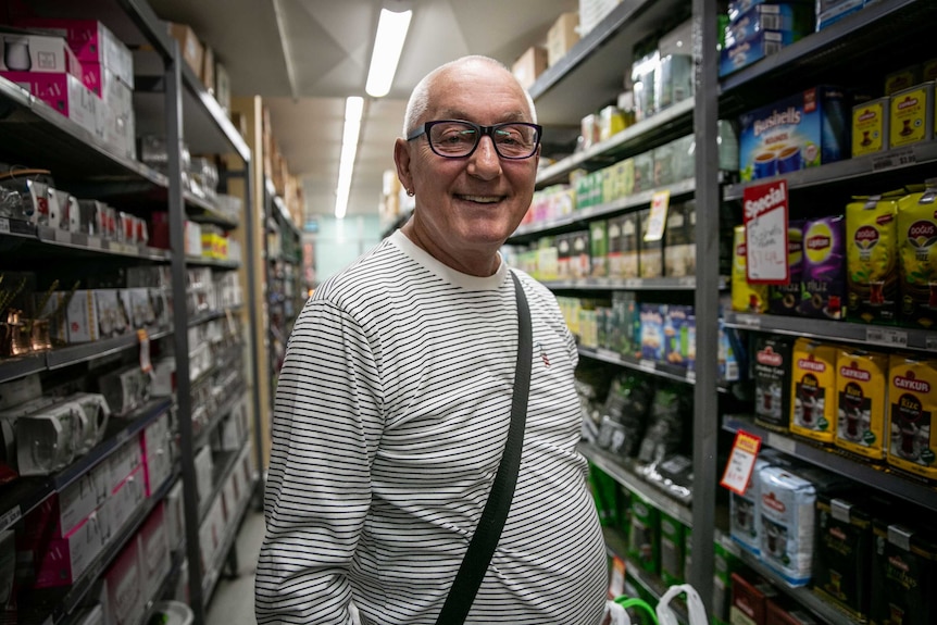 A man smiling in a supermarket aisle