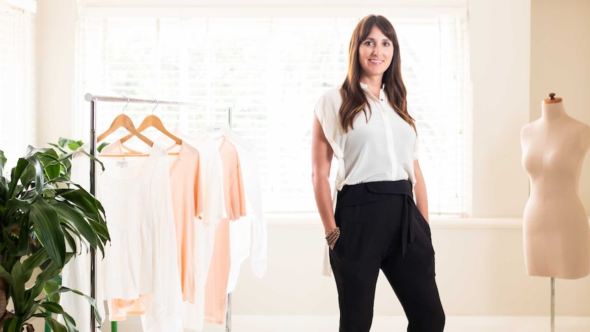 Fashion academic Lisa Heinze standing next to a rack of clothes.