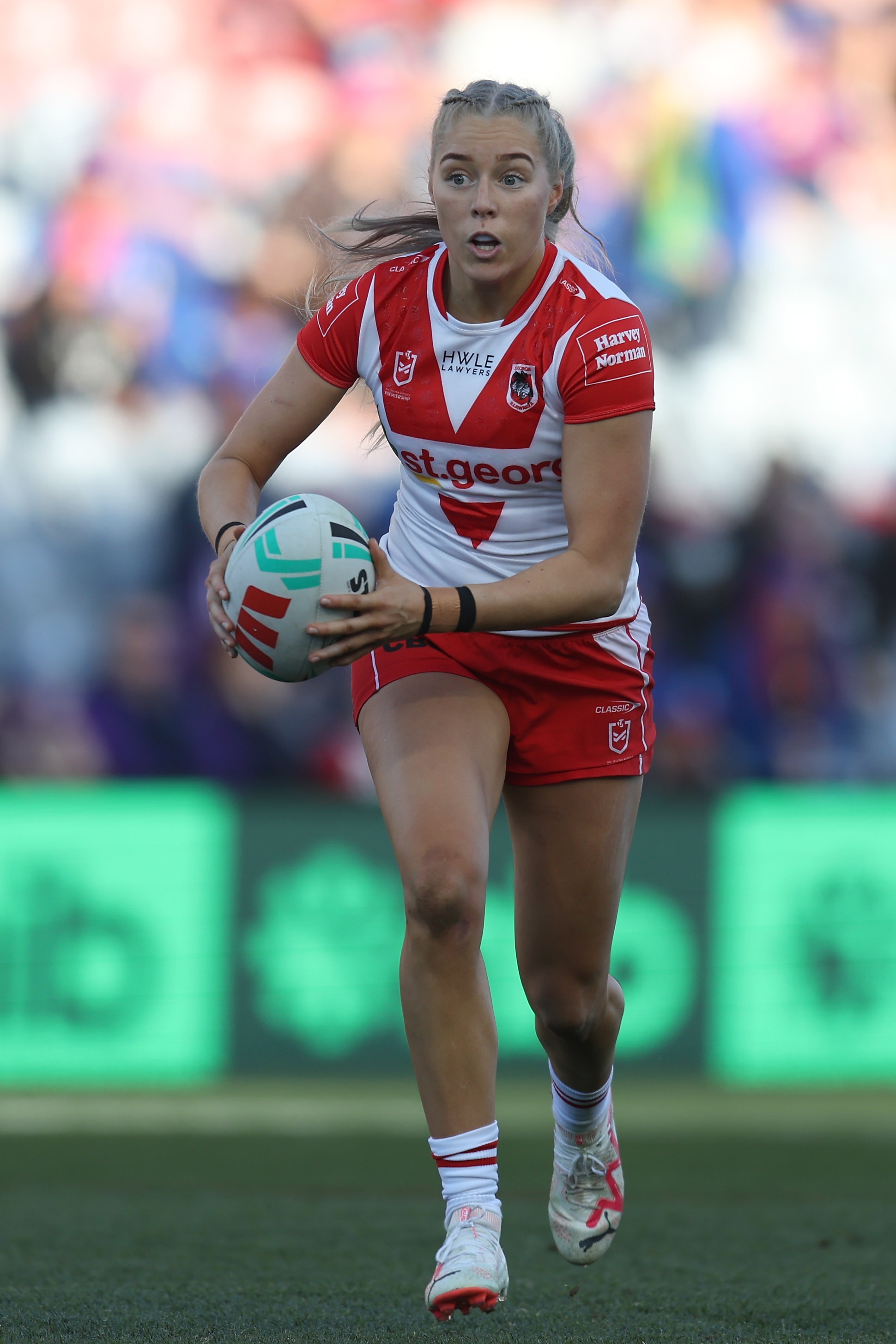 A St George Illawarra NRLW player runs with the ball in two hands during a match.