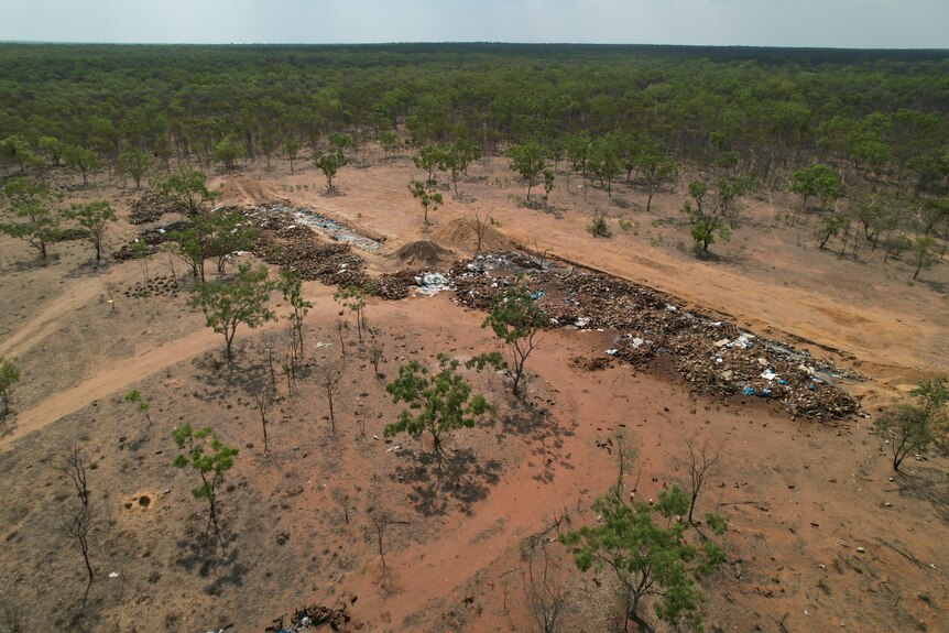An aerial view shows a piles of waste in an outback setting.