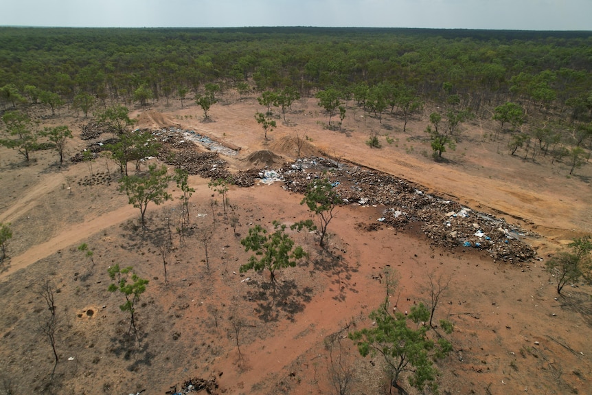 An aerial view shows a piles of waste in an outback setting.