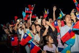 A group of people waving Taiwan and Palau flags and taking photographs.