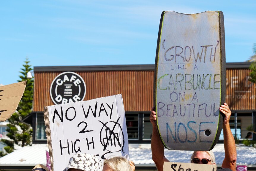 Placards decrying high-rise development held aloft at a protest at Point Danger