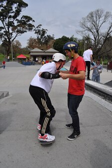 A man riding on a skateboard being held in place by another man