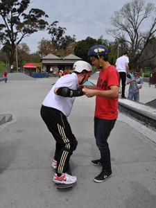 A man riding on a skateboard being held in place by another man