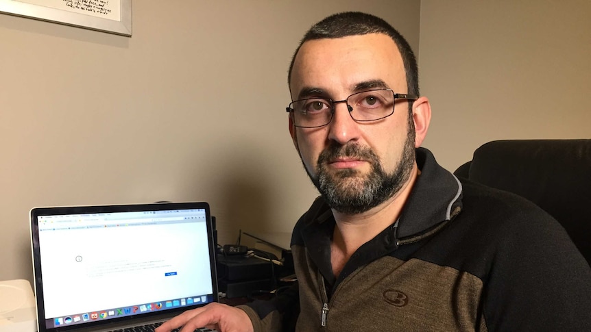 A man looks sad next to his laptop.