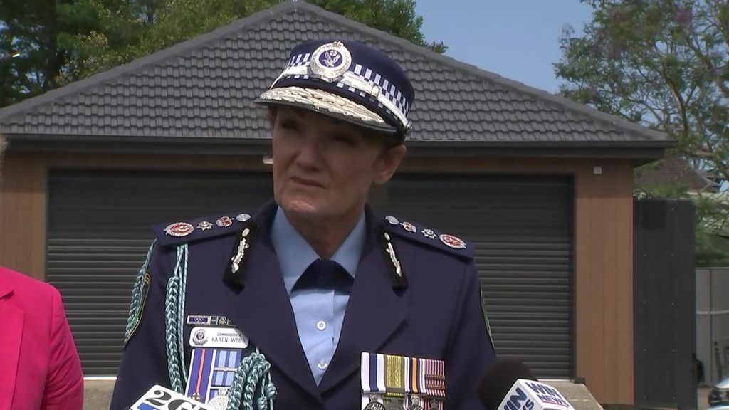 A woman in formal police uniform listening to a question at a media conference.