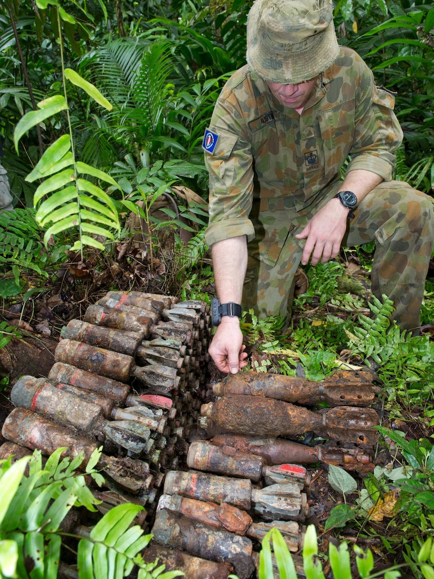 An Australian Army soldier examines World War II munitions uncovered by his Explosive Ordnance Disposal team during Operation RENDER SAFE 2014.