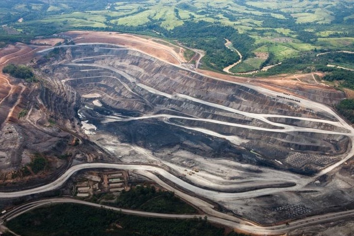 An aerial view overlooking an open cut mine with green areas surrounding.