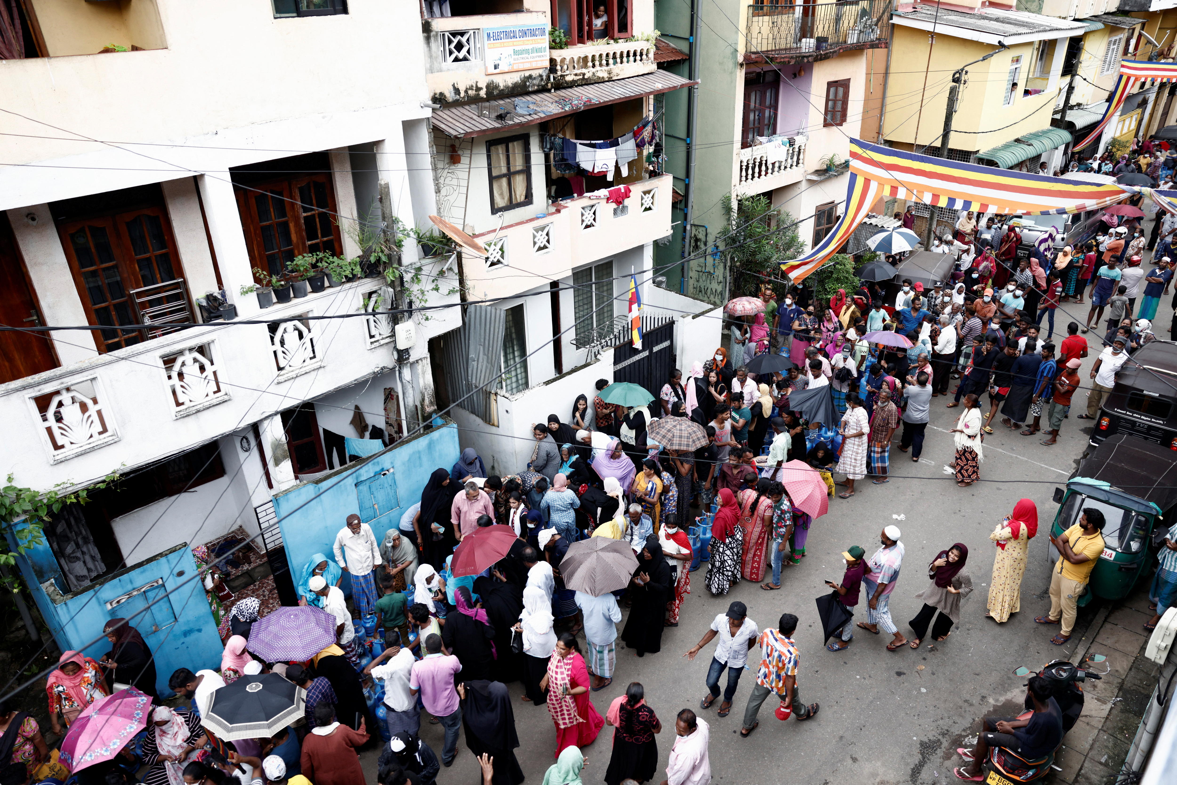 A queue of people crowd a busy street