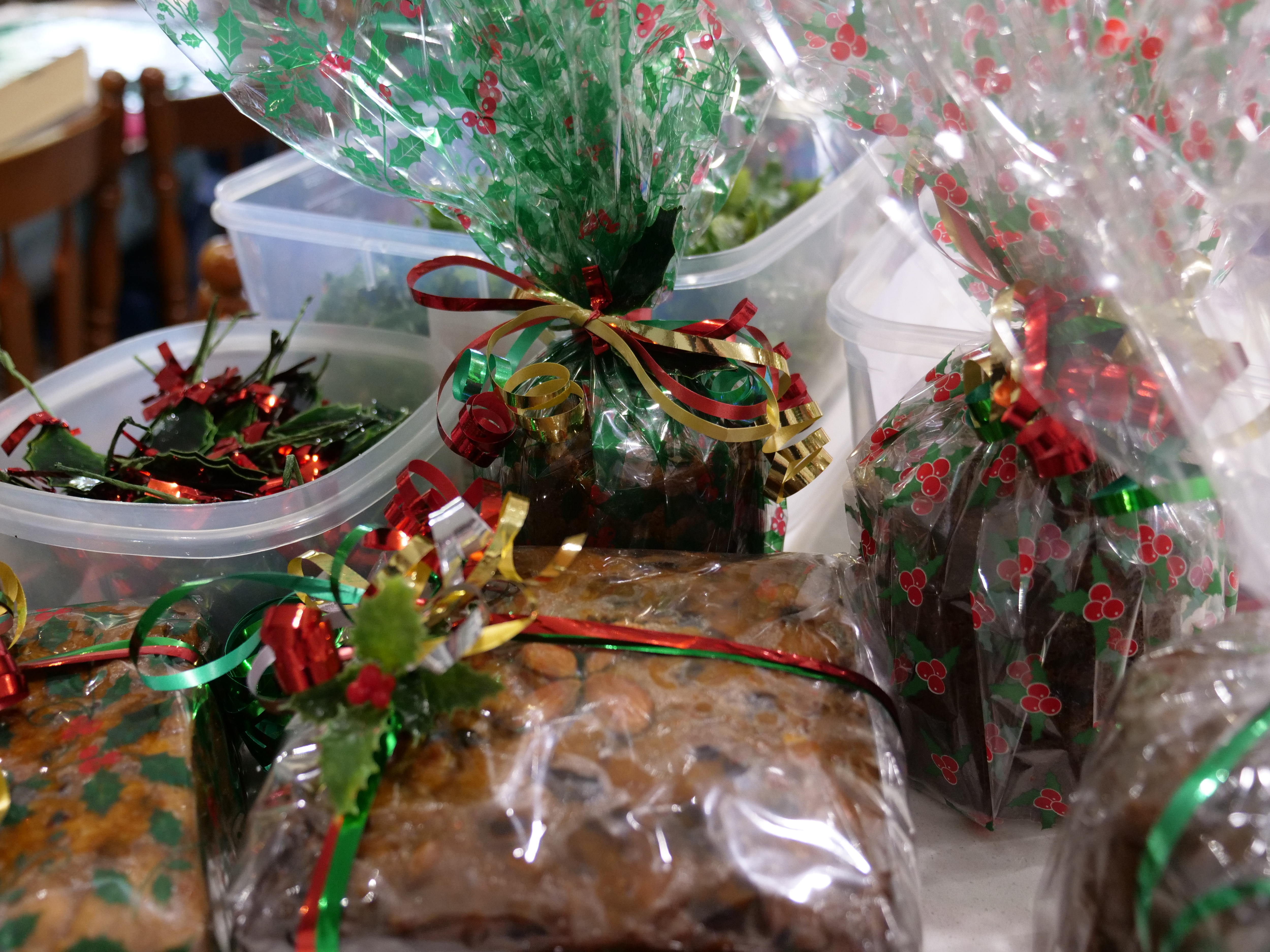 Pastel navideño envuelto en celofán con cinta rizada roja, dorada y verde.