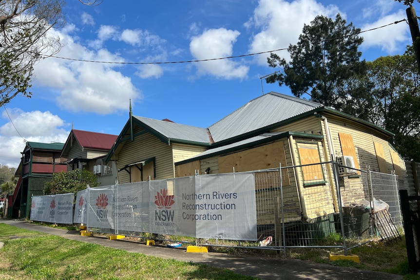 weatherboard home off its stumps, with security fence around it