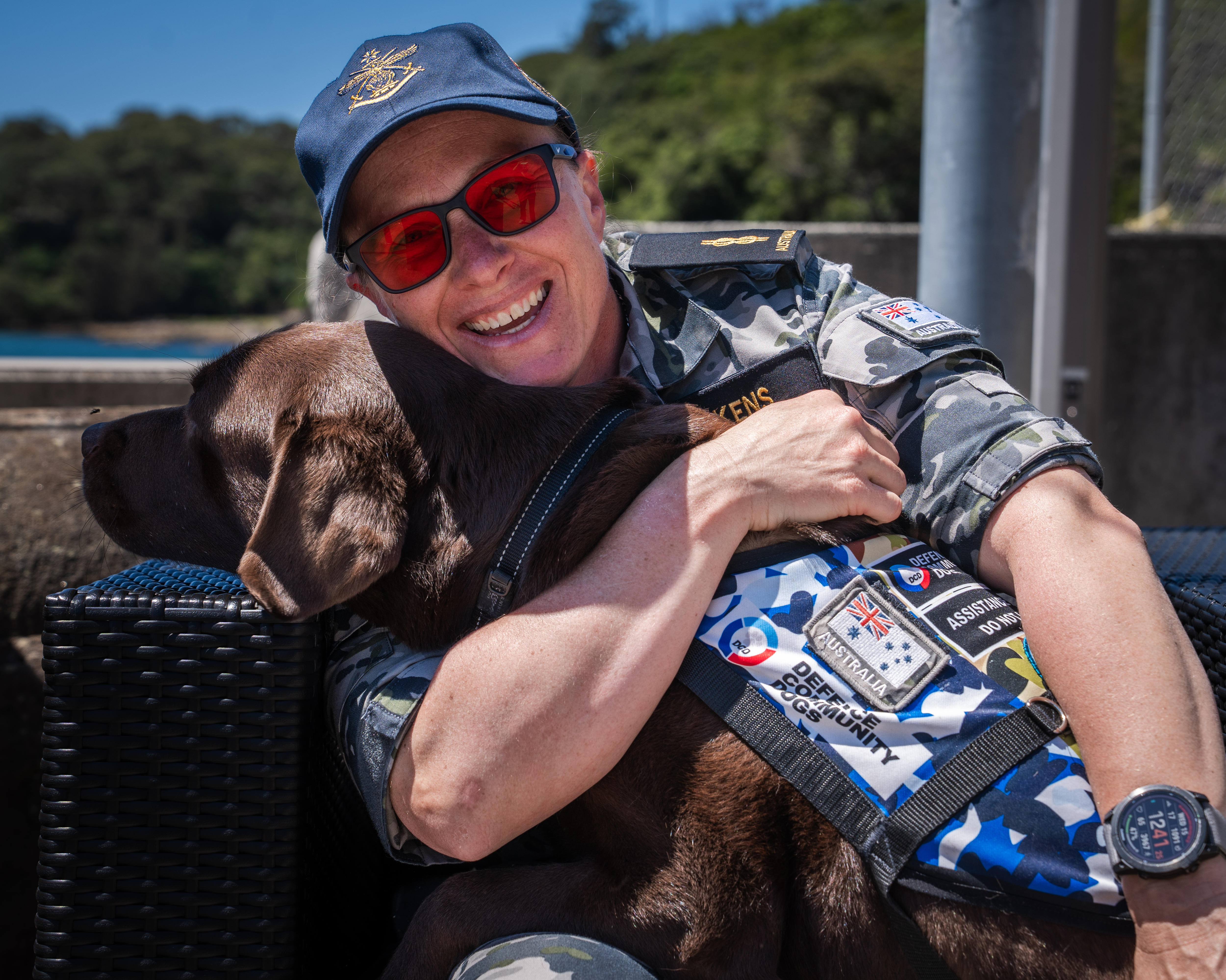 Taryn sonríe mientras abraza a su perro de servicio, Gigi, un labrador color chocolate.