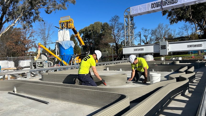 two men working on a construction site using a 3d printer