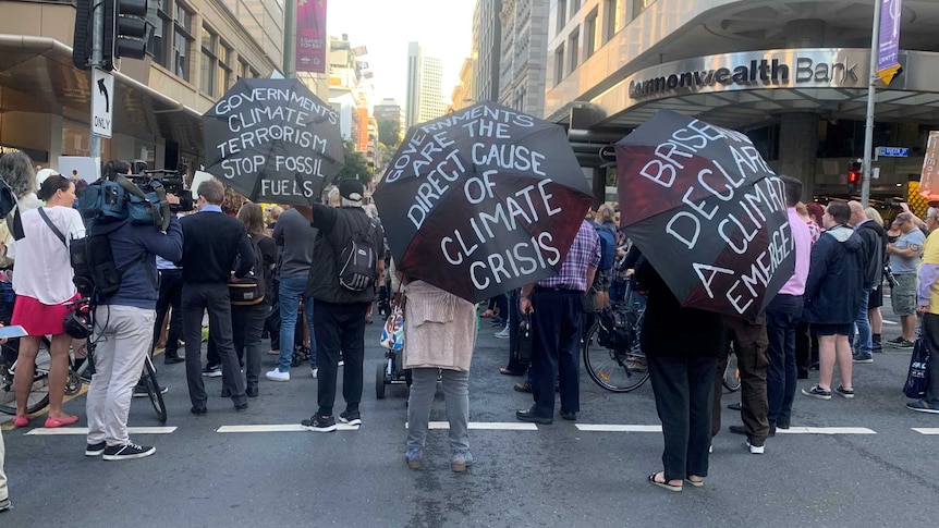 Climate change protesters hold up umbrellas with slogans.