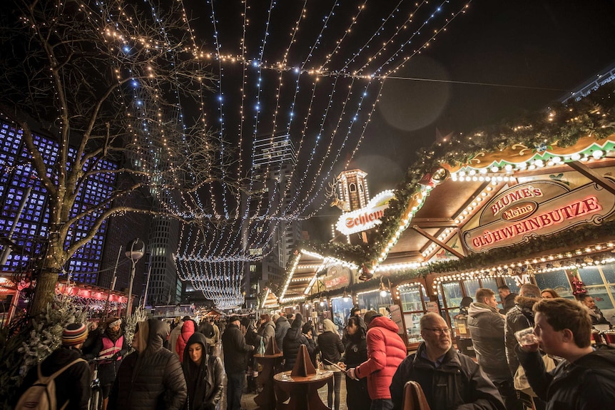 Visitors walk through the Breitscheidplatz Christmas markets under fairy lights.