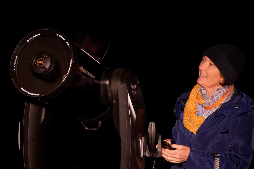 Astrotourism WA CEO and founder Carol Redford operating a giant telescope at night.