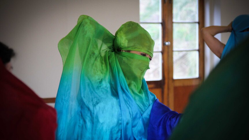 A woman dancing with a scarf around her face.