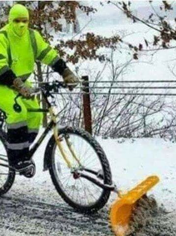 Man on a bike shovelling snow.