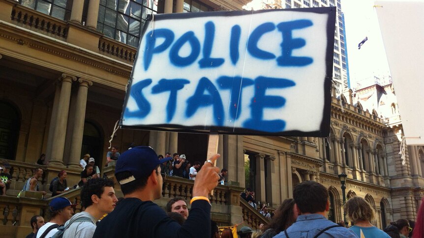 A protester holds a sign that reads "Police State" on a Sydney street.