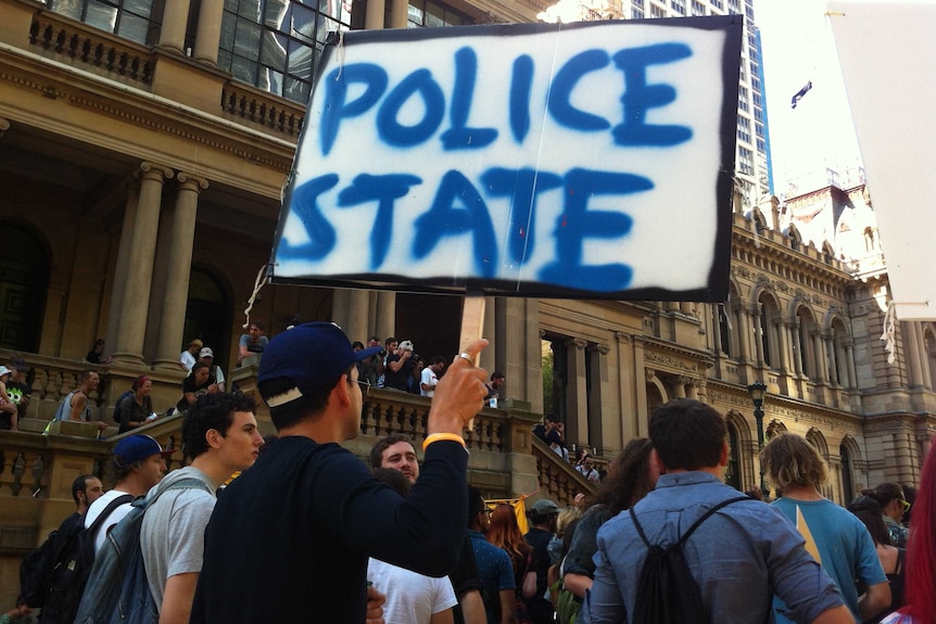 A protester holds a sign that reads "Police State" on a Sydney street.