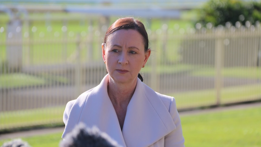 Queensland Health Minister Yvette D'Ath stand in front of lectern at race track.