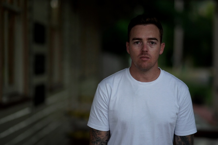 A man looks reflective in a green backyard setting