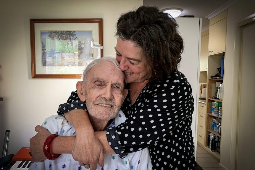 Elderly man being hugged by his daughter