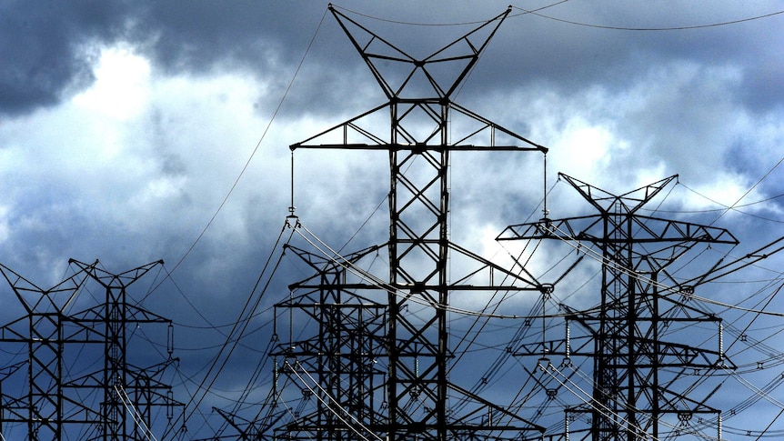 power lines on tall structures in front of a dark sky of clouds