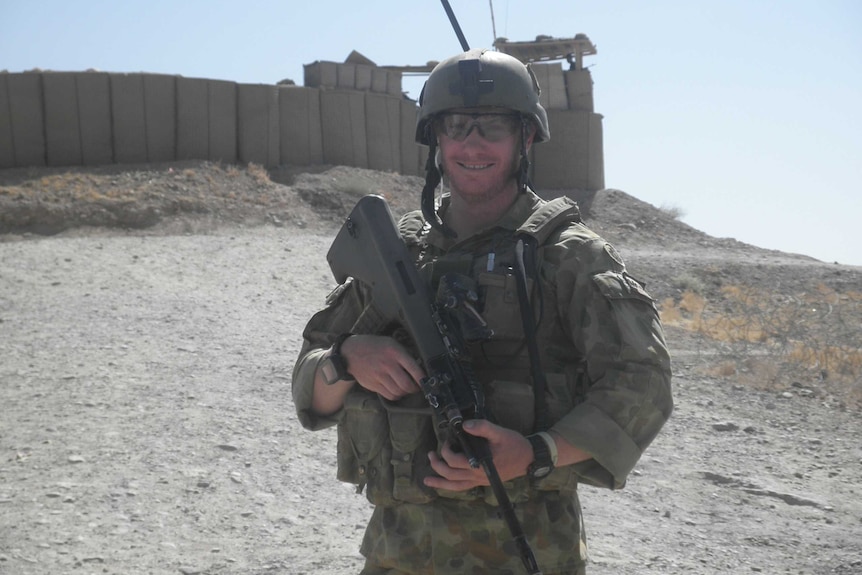 Young soldier in battle gear, holding a rifle, in the desert