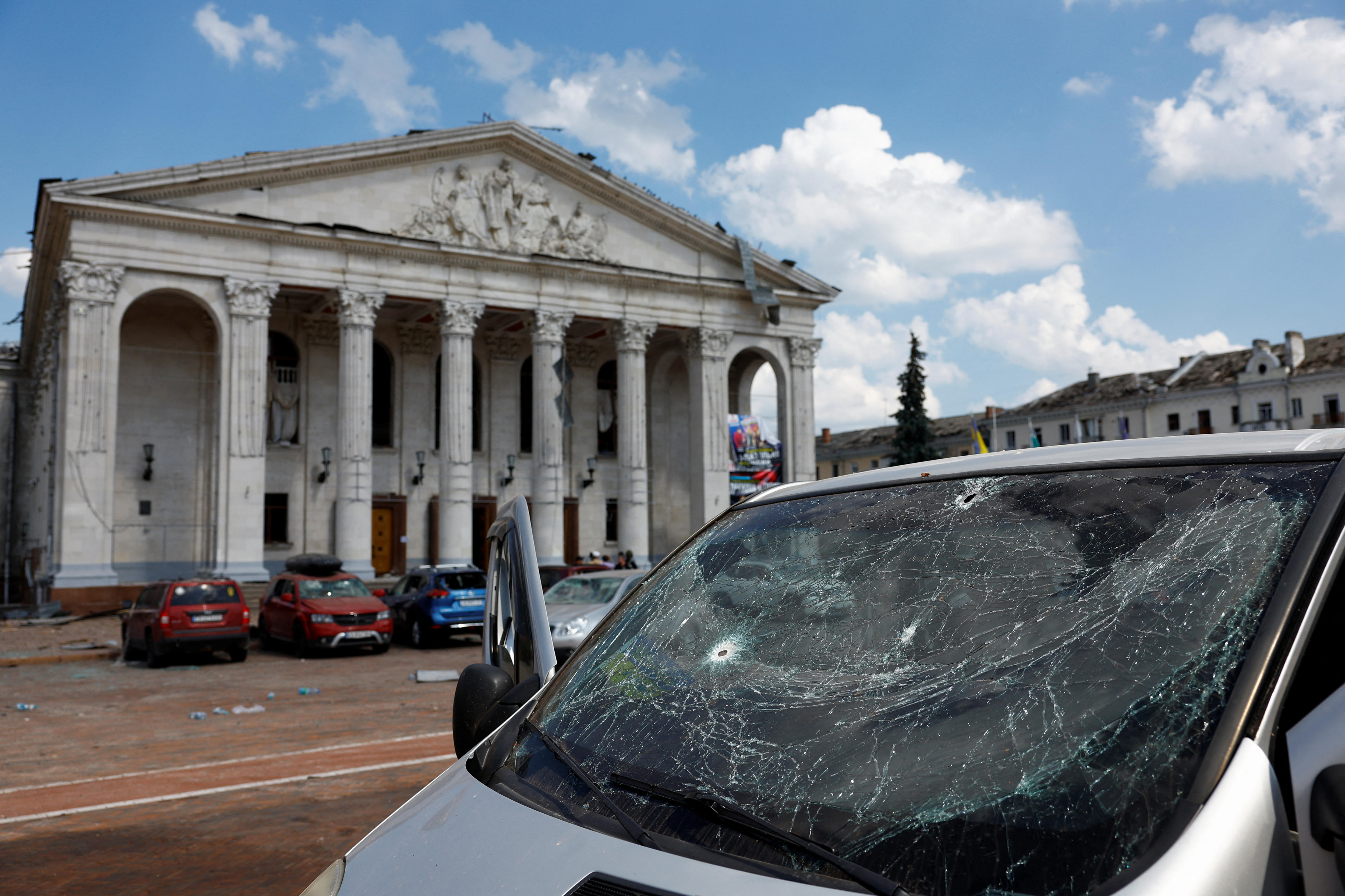 car with broken window in front of damaged building 